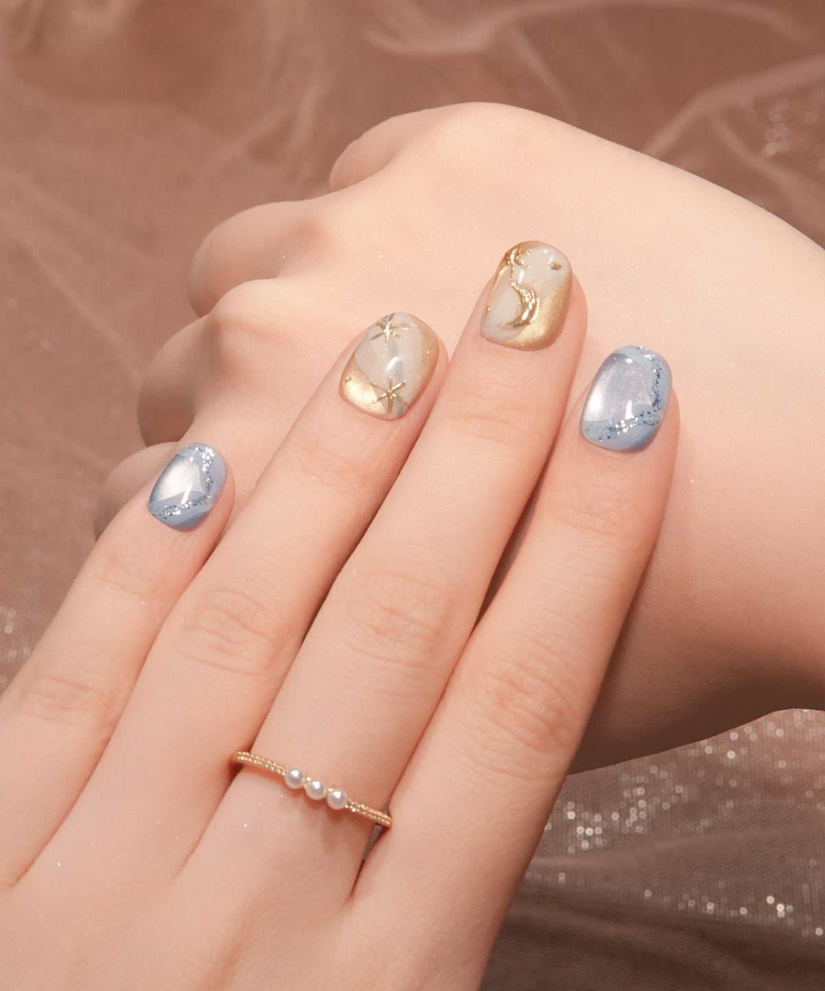 淡いブルーのマグネットと立体的なゴールドの月星モチーフをあしらったショートラウンドのジェルネイルチップ